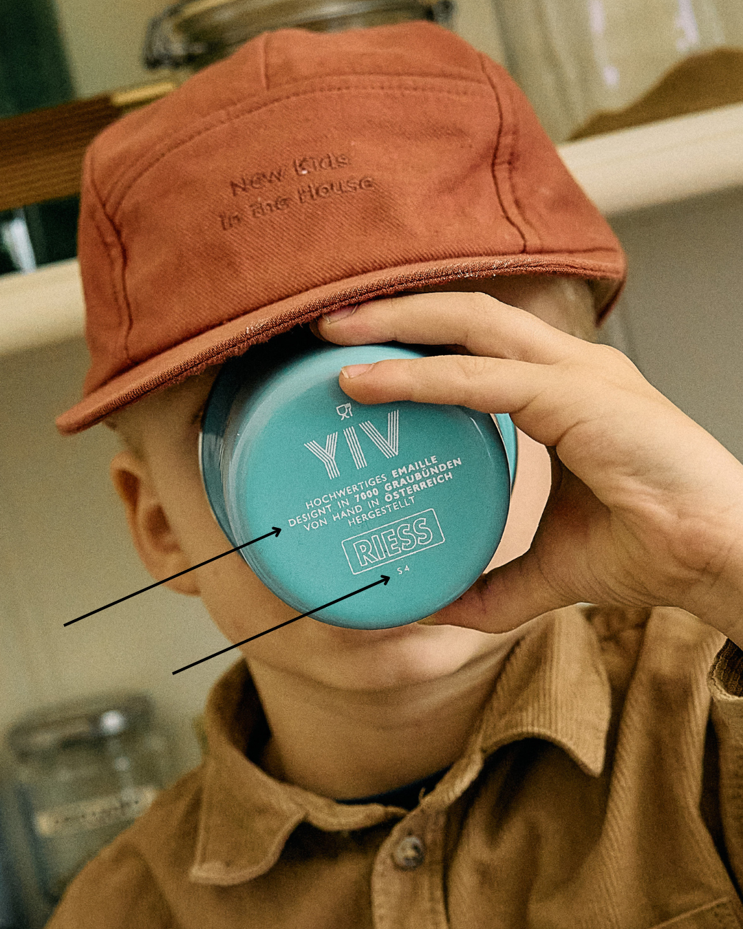 Kind trinkt aus einem türkisen YIV Emaille-Becher; auf dem Becherboden sind die Markierung «Design in 7000 Gründen – von Hand hergestellt» und das RIESS-Siegel zu sehen